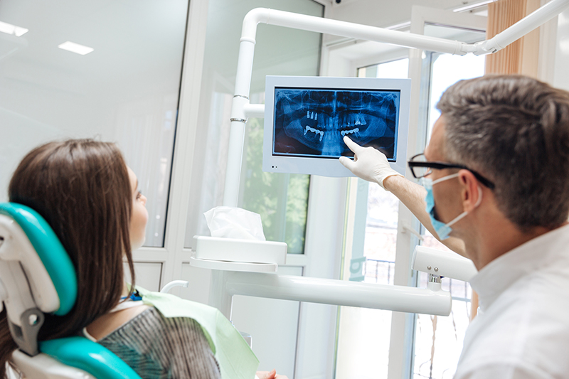 Male dentist shows a patient x-ray of teeth in clinic